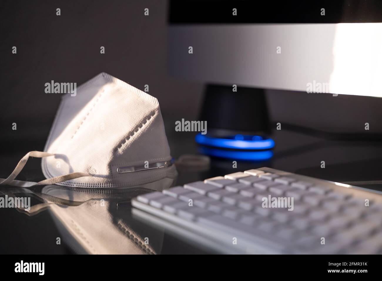 a mask on a table with keyboard and monitor Stock Photo