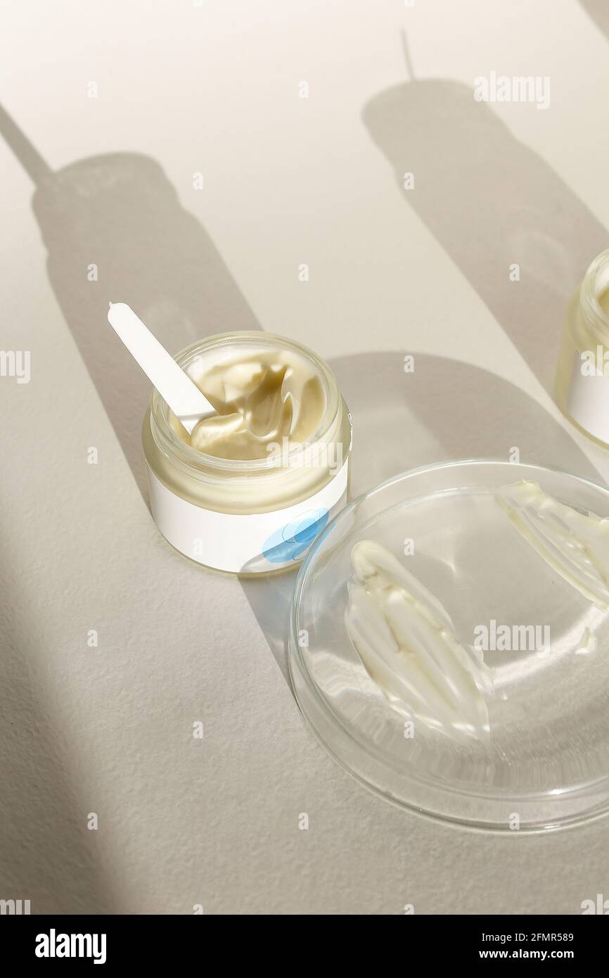 Cosmetic cream container with face or body cream on neutral background