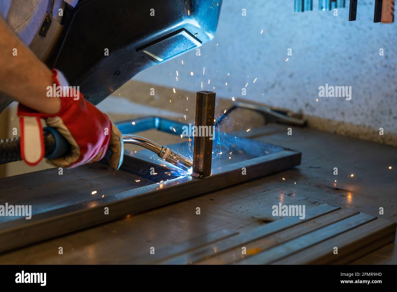 Detail of a man welding steel frames in a and metal works