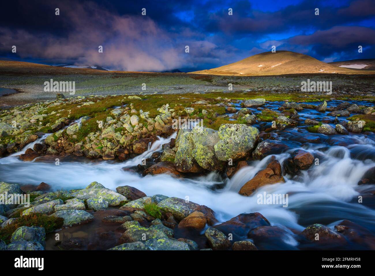 River stream and mountains in amazing early morning light in Dovrefjell national park, Dovre, Norway, Scandinavia. Stock Photo