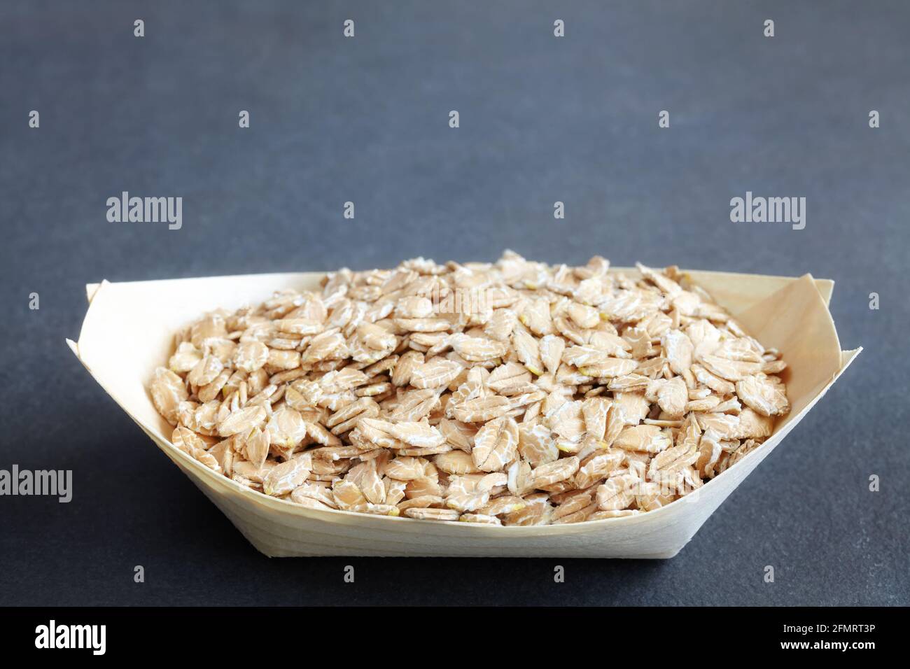 Organic spelt flakes in a wooden eco container, selective focus, space for text. Stock Photo