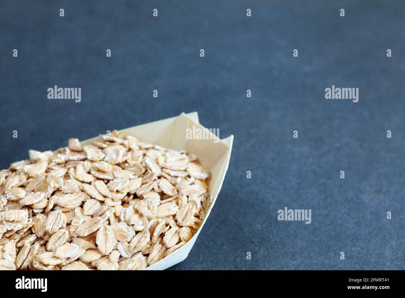 Organic spelt flakes in a wooden eco container, selective focus, space for text. Stock Photo