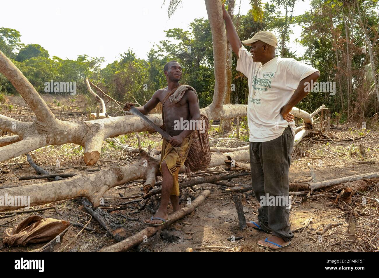 Farmer talking to Liberian conservationist about the tropical forest he has just cleared to make a living, illustrating how complex conservation is. Stock Photo