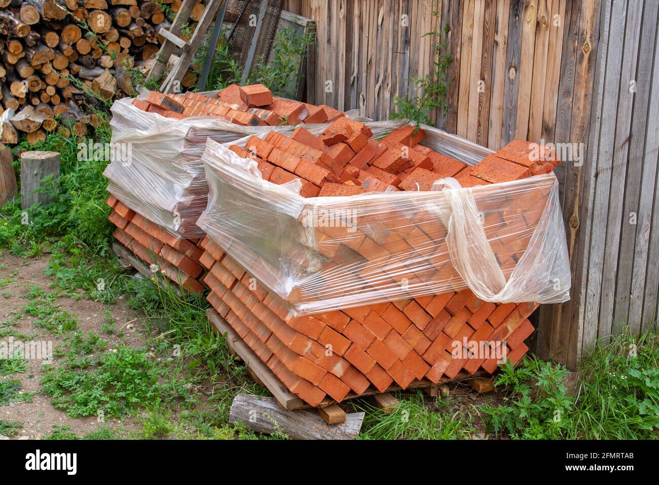 Old brick lies on pallets and wrapped in plastic wrap. Horizontal image ...