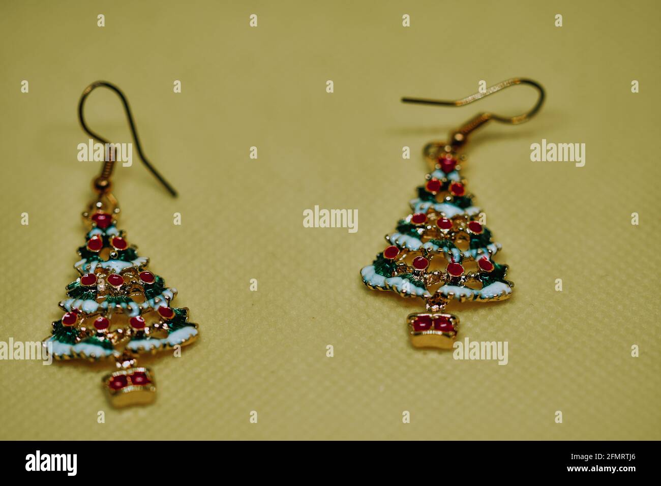 Pair of golden enameled earring in the shape of Christmas trees with ornaments and presents Stock Photo