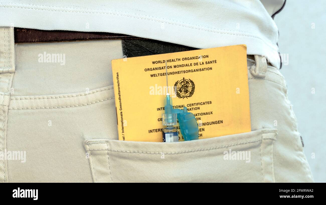 Vaccination certificate and vaccination syringe in trouser pocket Stock Photo