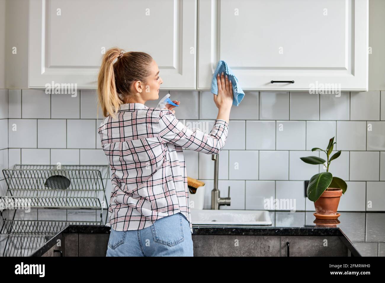 Woman washes cleaning kitchen set with rag or cloth. House