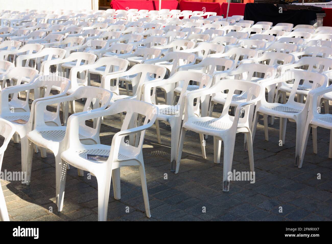 Perspective of some white plastic chairs in which the public that comes to the venue to witness an outdoor show must sit Stock Photo
