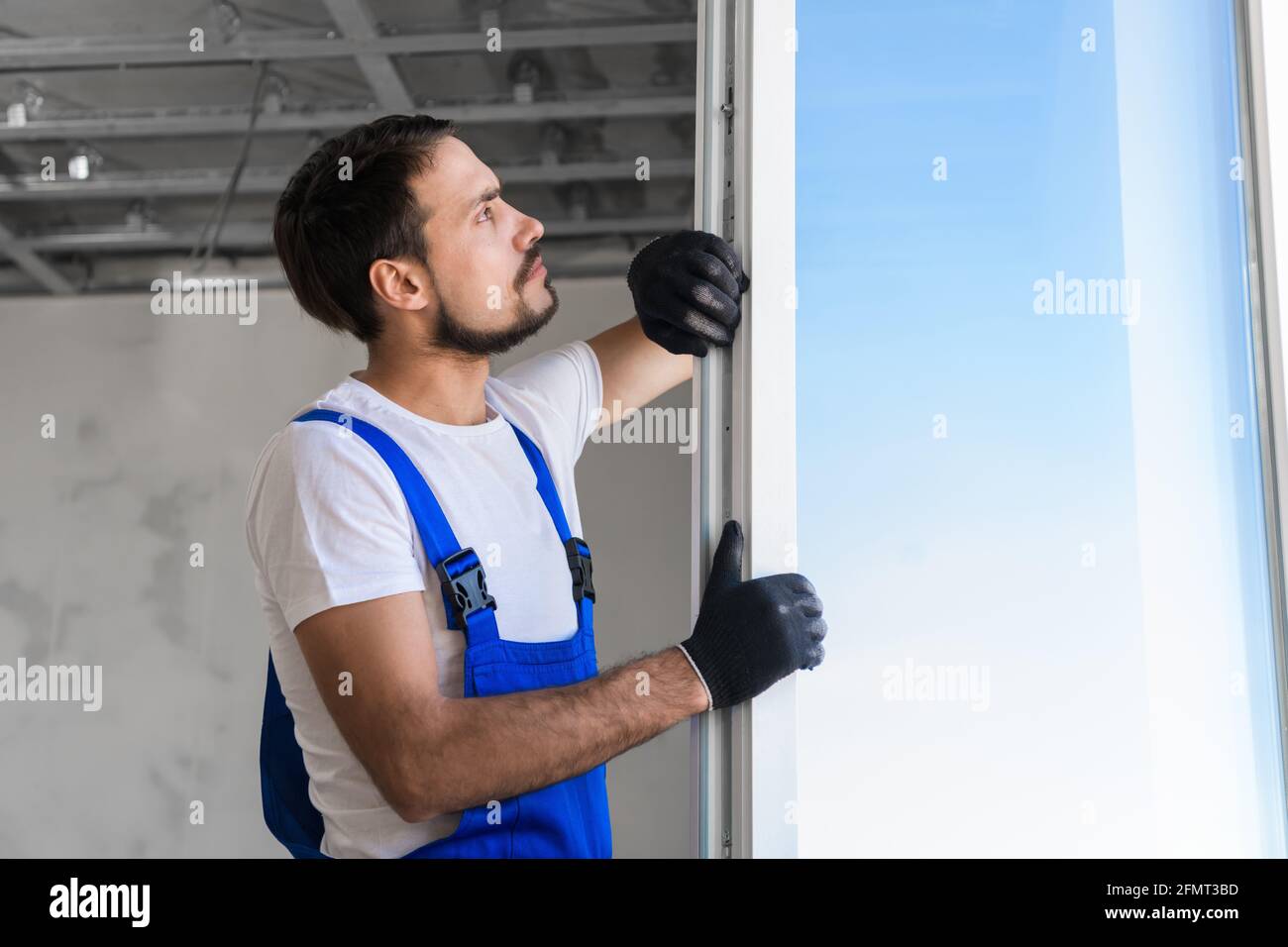 Bearded worker checks the plastic window in the apartment Stock Photo
