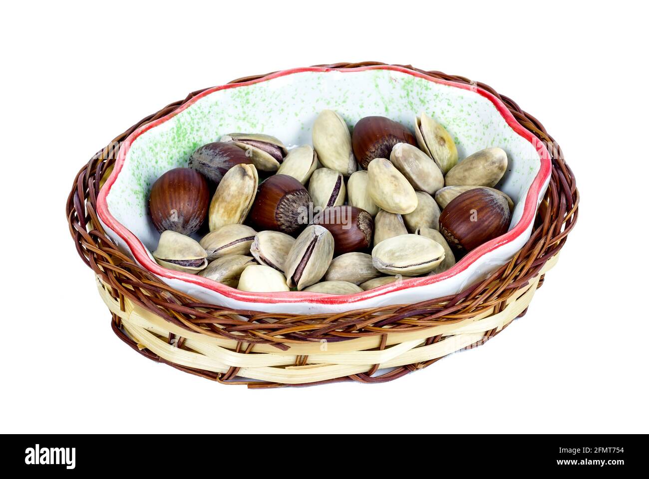 hazelnuts and pistachios in a wicker basket in bowl isolated on white background Stock Photo