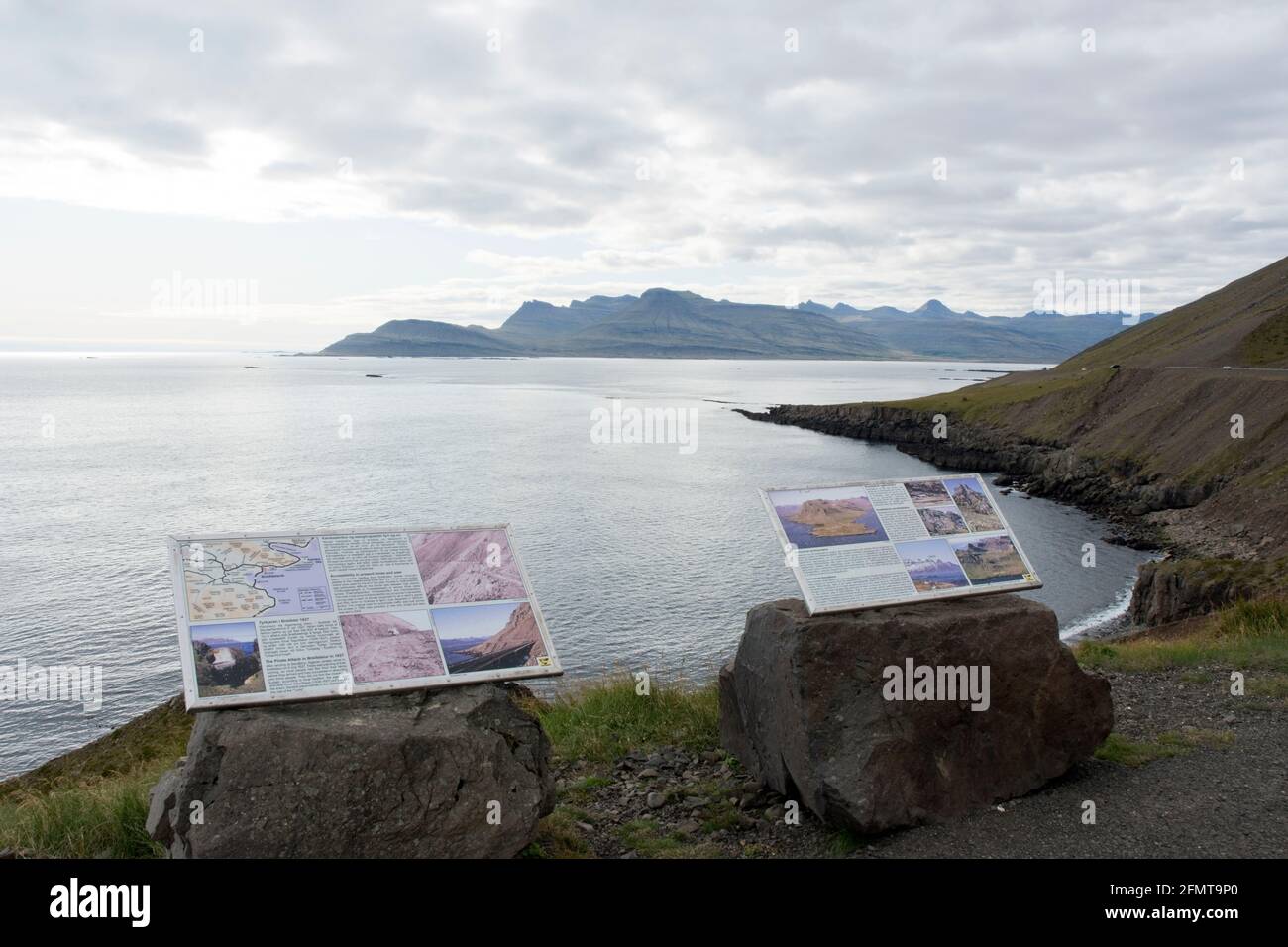 An informational sign describes the geology of East Iceland at the Kambanes peninsula, south of the village of Stodvarfjordur, Iceland. Stock Photo