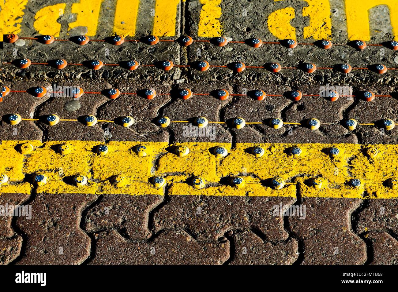 Looking down at studs and warning markings on the edge of a platform in a train station. Stock Photo