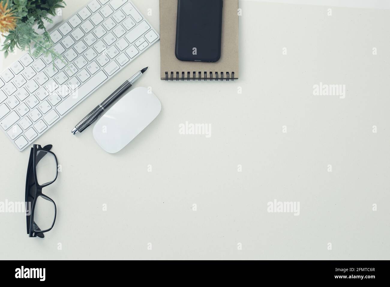 White keyboard mouse glasses pen notepad phone flower in pot on white background Stock Photo