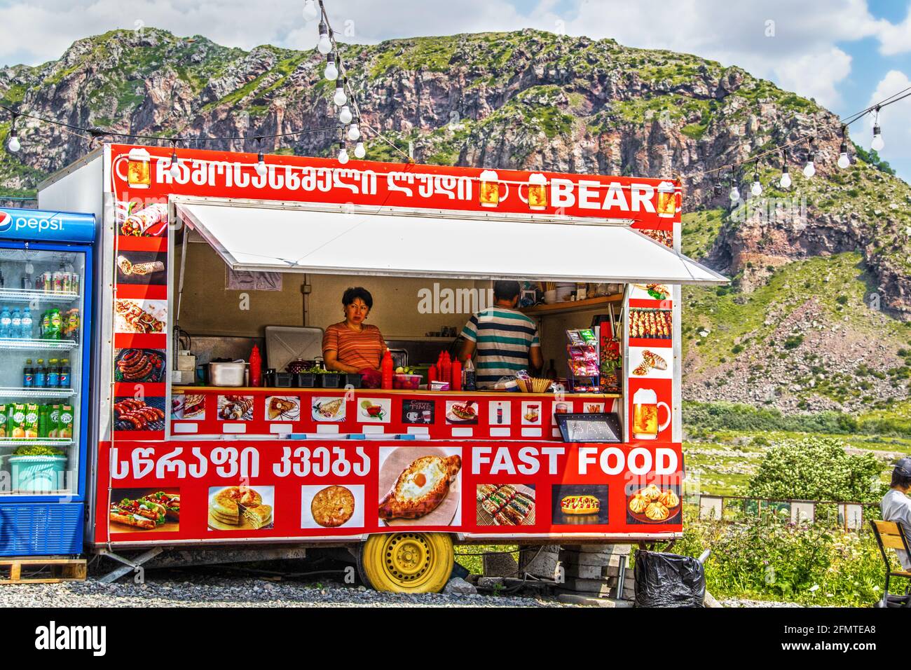 07 01 2019 Stepantminda Georgia - Street food vendor with two servers inside and lights strung up outside advertising traditional Georgian food and pi Stock Photo