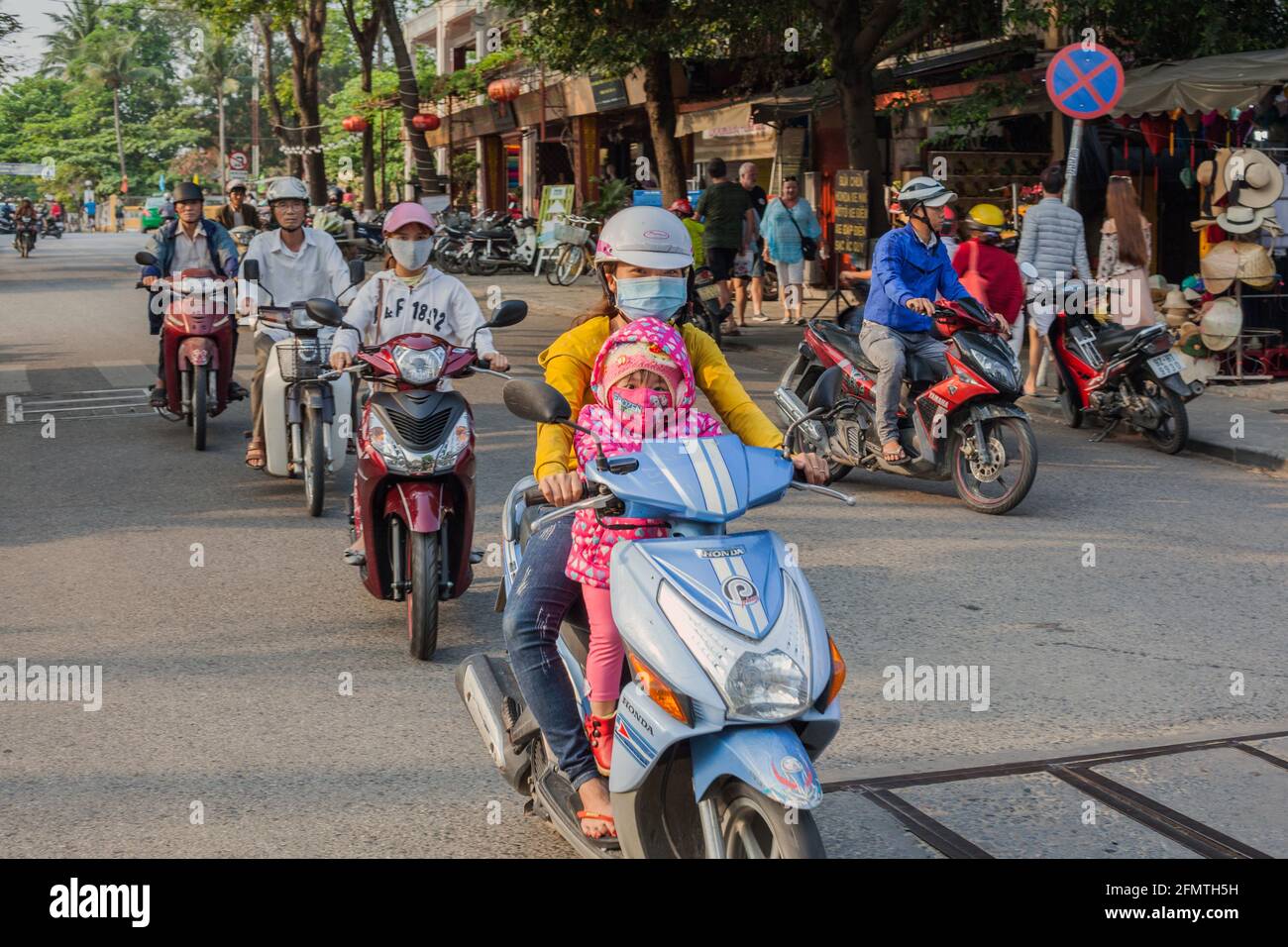 Vietnamese female driving scooter with young child at the front, old town, Hoi An, Vietnam Stock Photo
