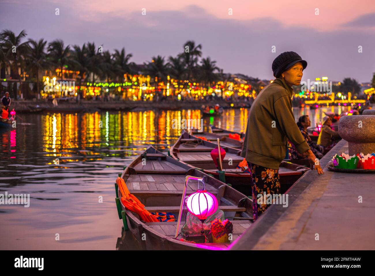 Elderly Vietnamese boat lady waiting for customers by the riverside, Hoi An, Vietnam Stock Photo
