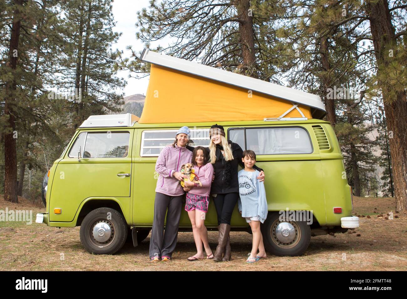 Portrait of two women, two children and dog in front of green VW van Stock Photo