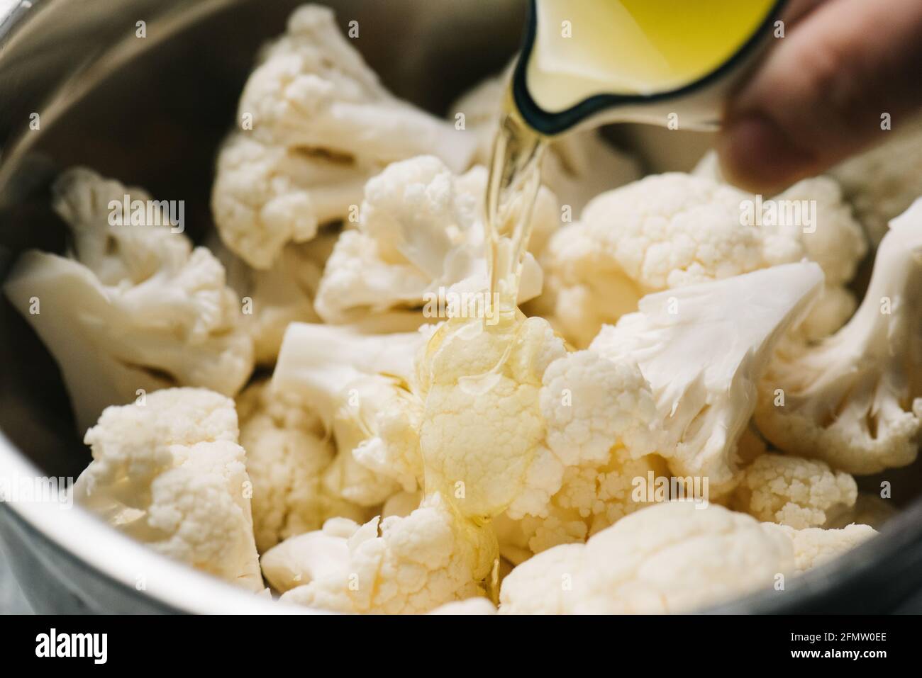 Pouring oil over cauliflower before roasting Stock Photo Alamy