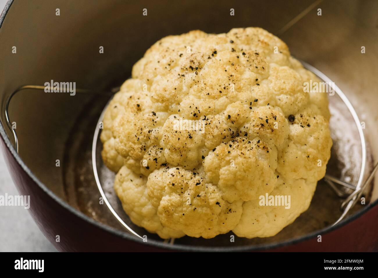 Golden roasted cauliflower head in a Dutch oven Stock Photo