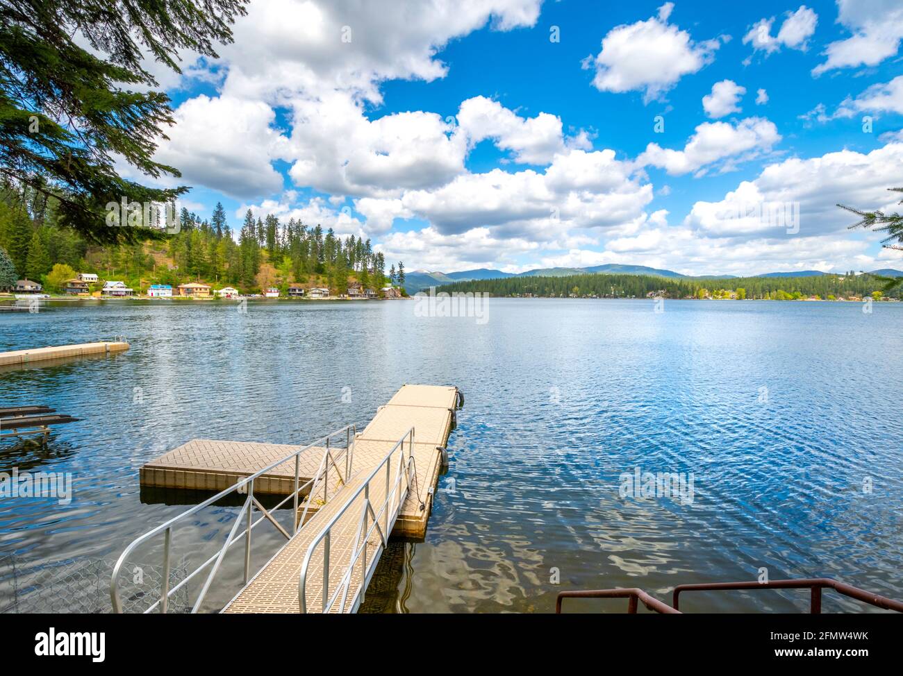 A small dock from a home in the rural community of Newman Lake, Washington, USA with other waterfront homes and boat slips in view. Stock Photo
