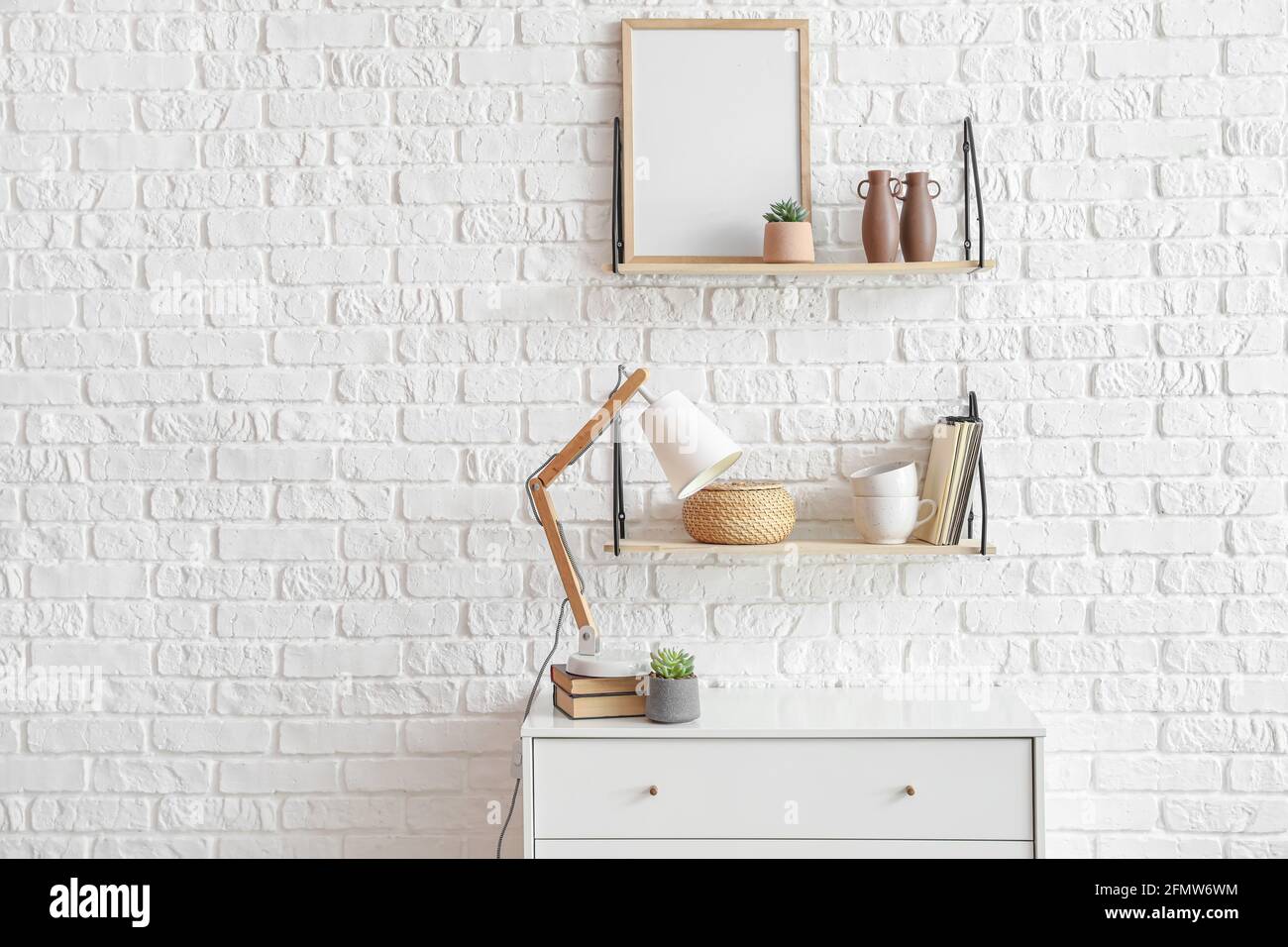 Chest of drawers and shelves with decor near brick wall Stock Photo Alamy