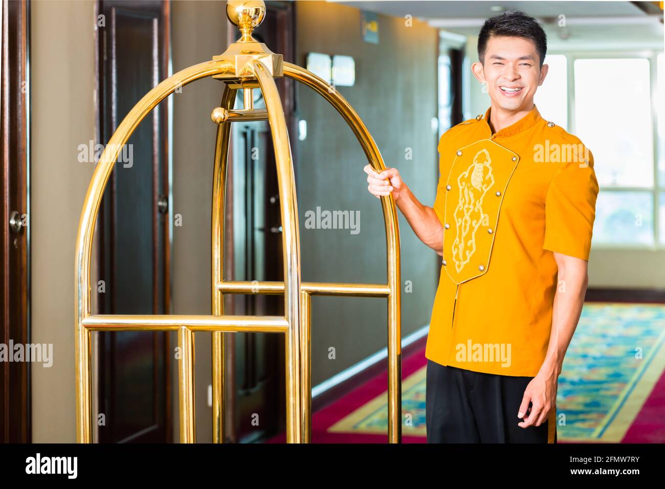 Asian Chinese baggage porter or bell boy or page bringing the suitcase
