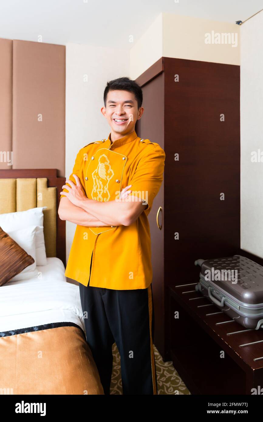 Asian Chinese baggage porter or bell boy or page bringing the suitcase