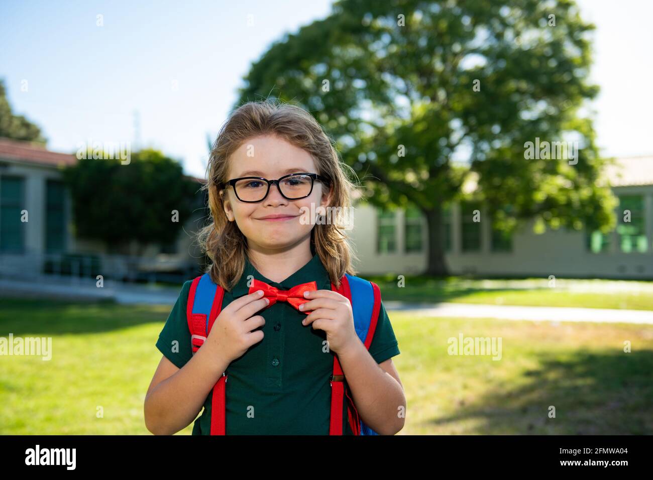 Child with rucksacks in the school park. Pupils with backpacks outdoors. Nerd pupil ties a