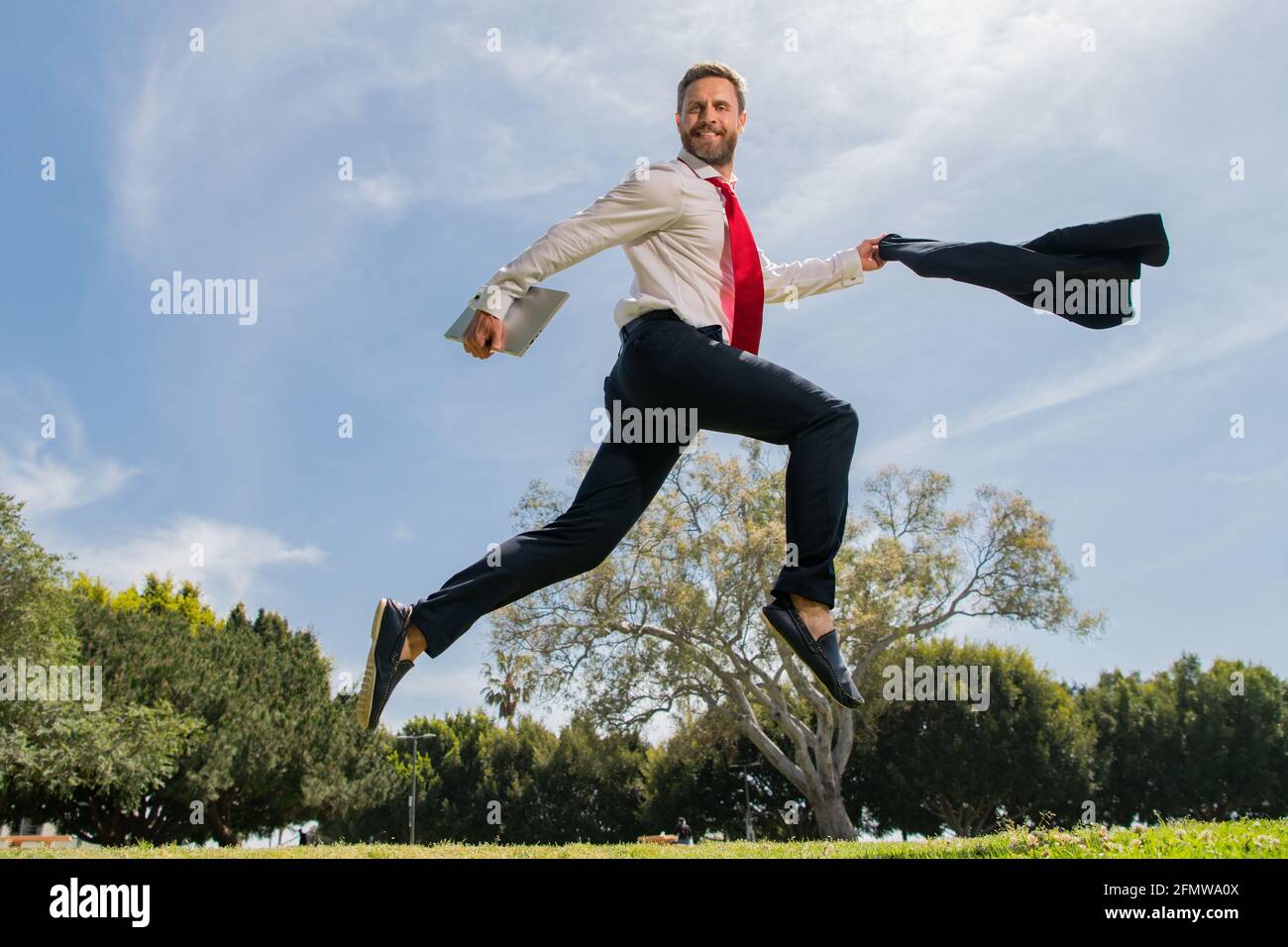 Business man in suit jumping over urban park. Fast business concept. Stock Photo