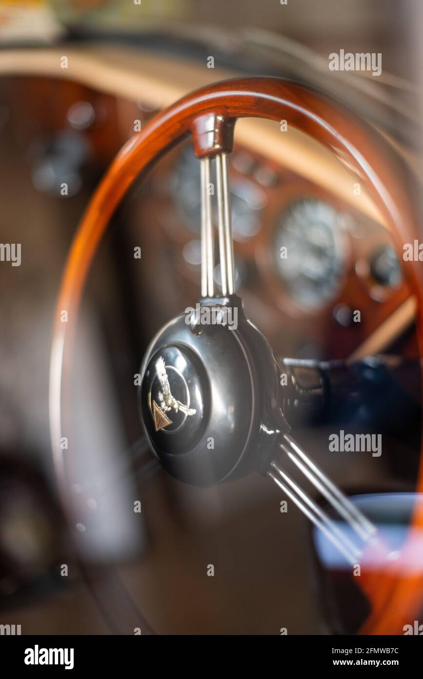 Shiny Wooden Steering Wheel and blur dashboard through car's window with reflection inside vintage 1960s Alvis Classic Car, New Zealand Stock Photo