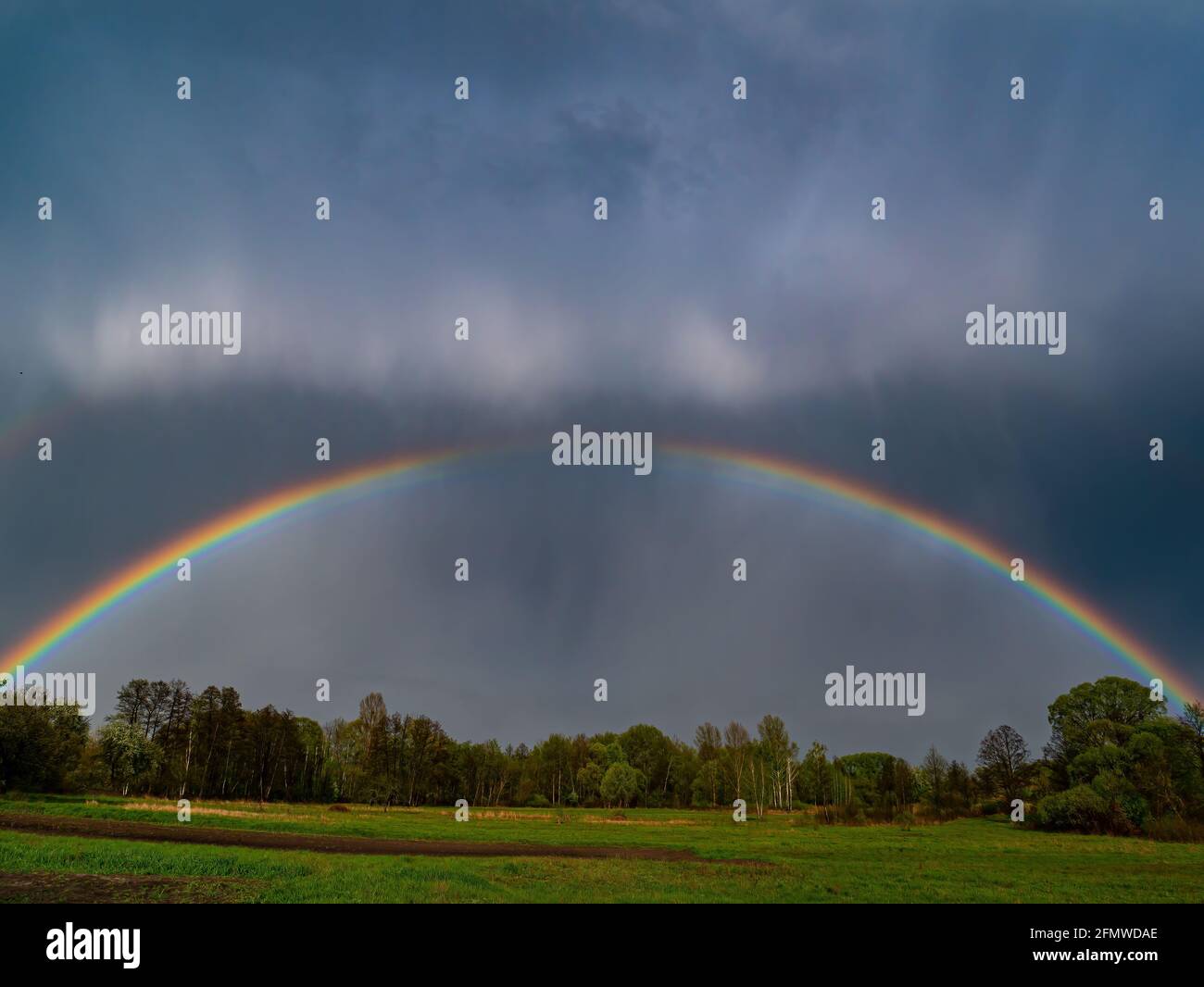 Rainbow with rain clouds in the sky. Colored rainbow. Color spectrum ...