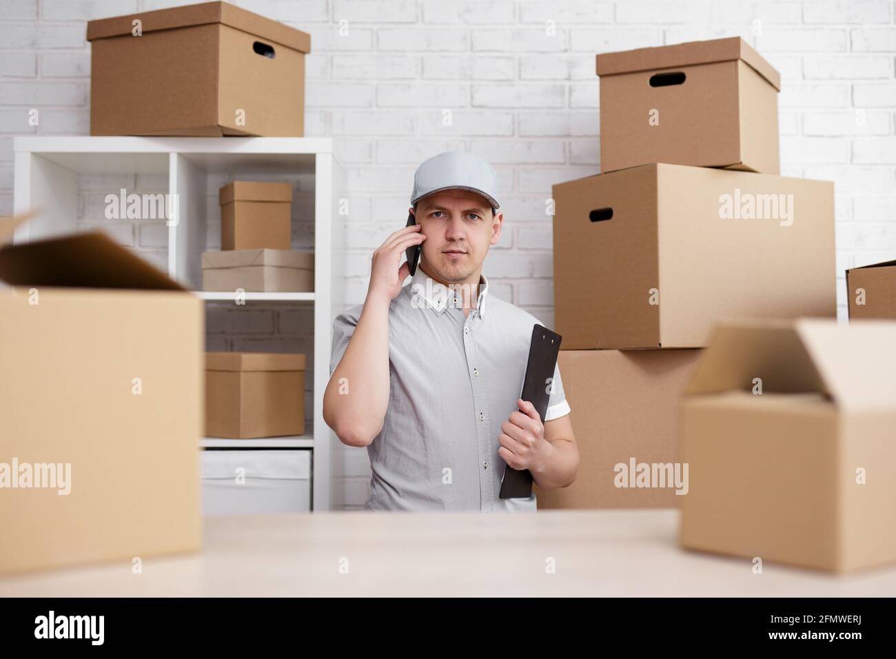 business and work concept - postman or storage worker talking by phone ...