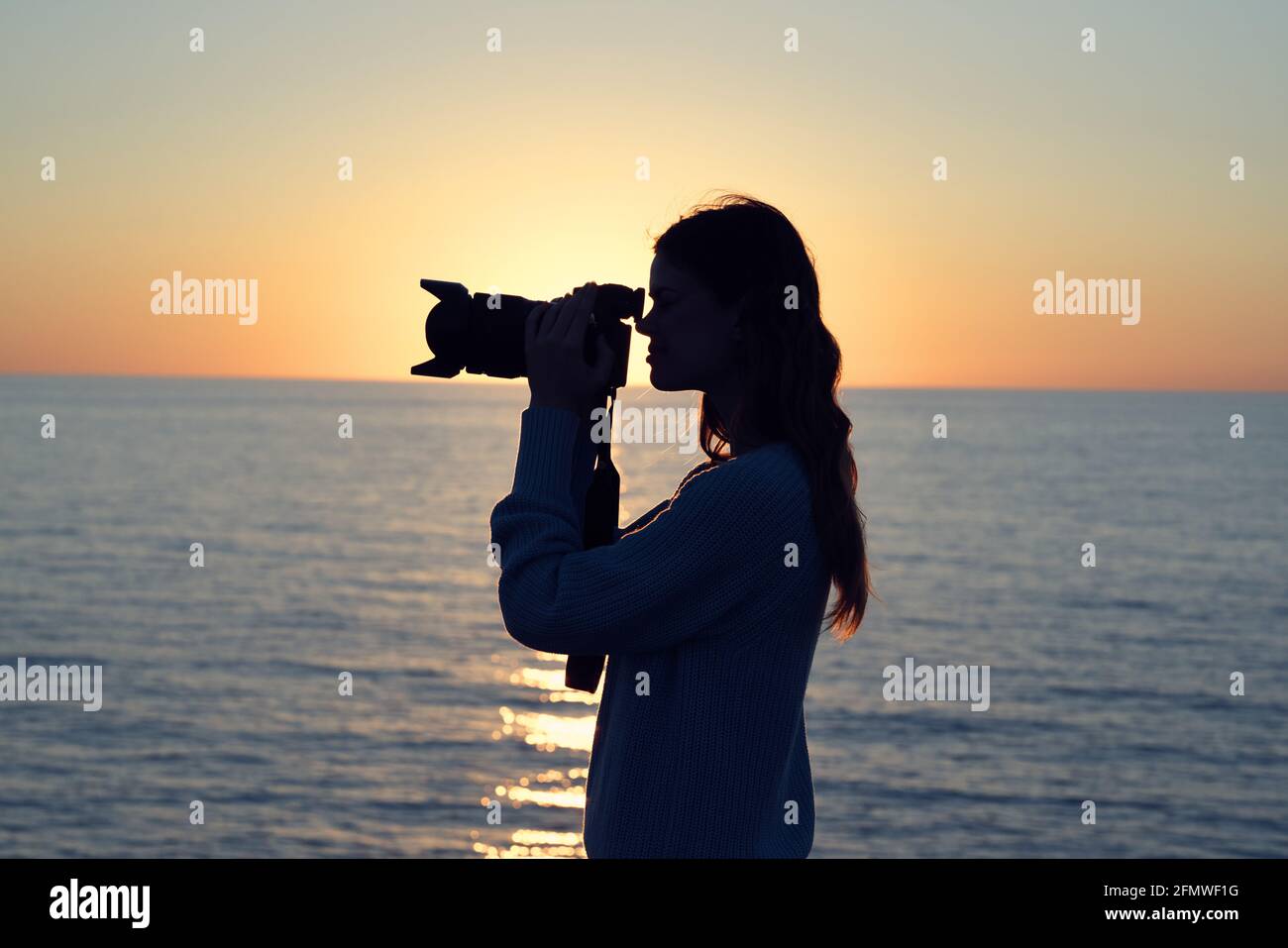 Woman with camera landscape sunset sea sun model Stock Photo - Alamy