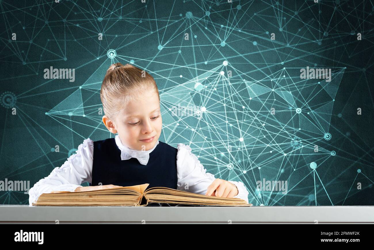 Smiling little girl sitting at desk with open book Stock Photo - Alamy