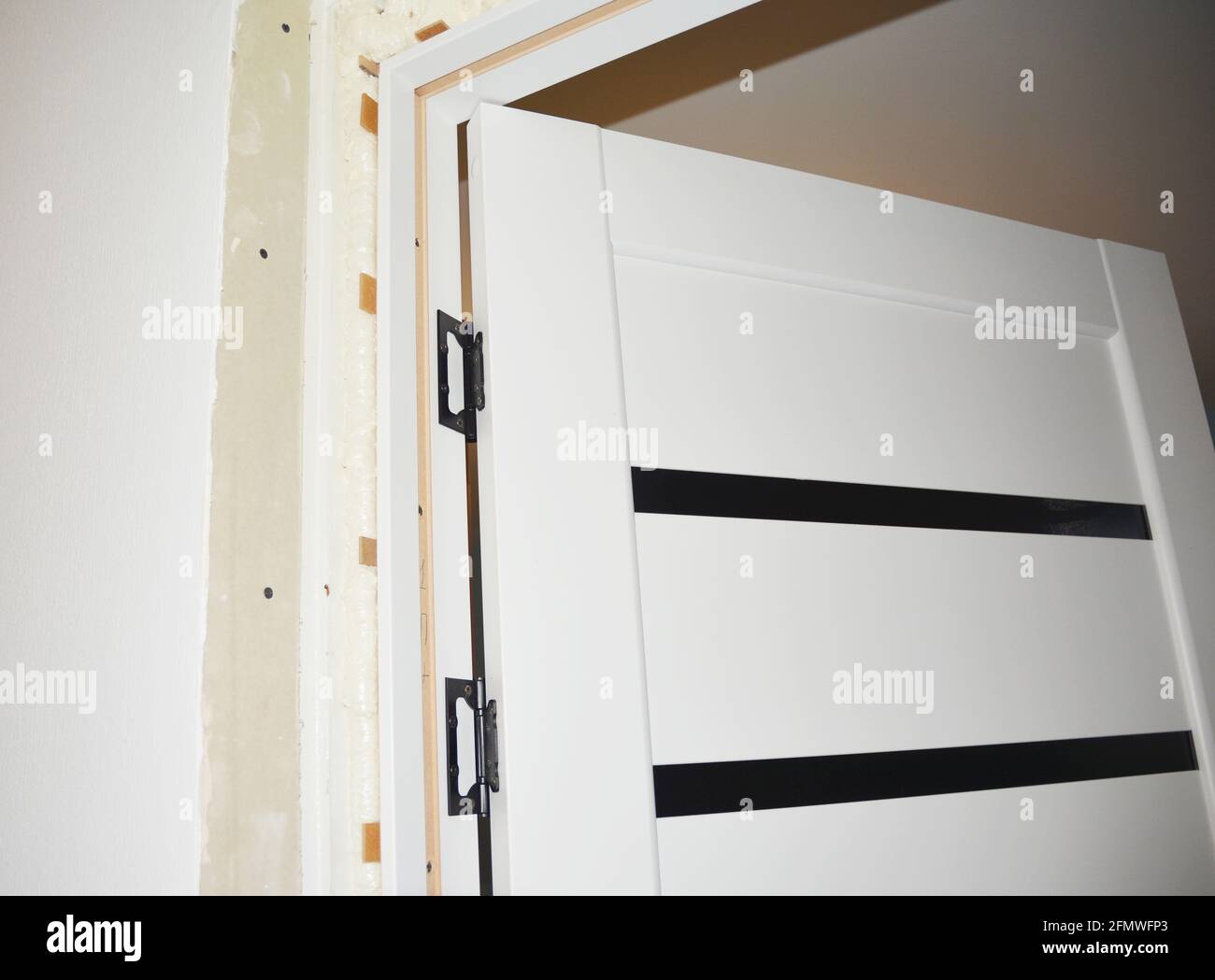 Interior white laminate door installation. Fitting the door, anchoring