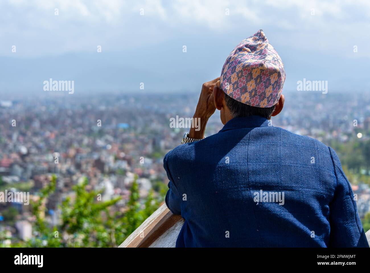 Nepali man wearing a topi contemplates Kathmandu city from Swayambhunath, in Nepal. Stock Photo
