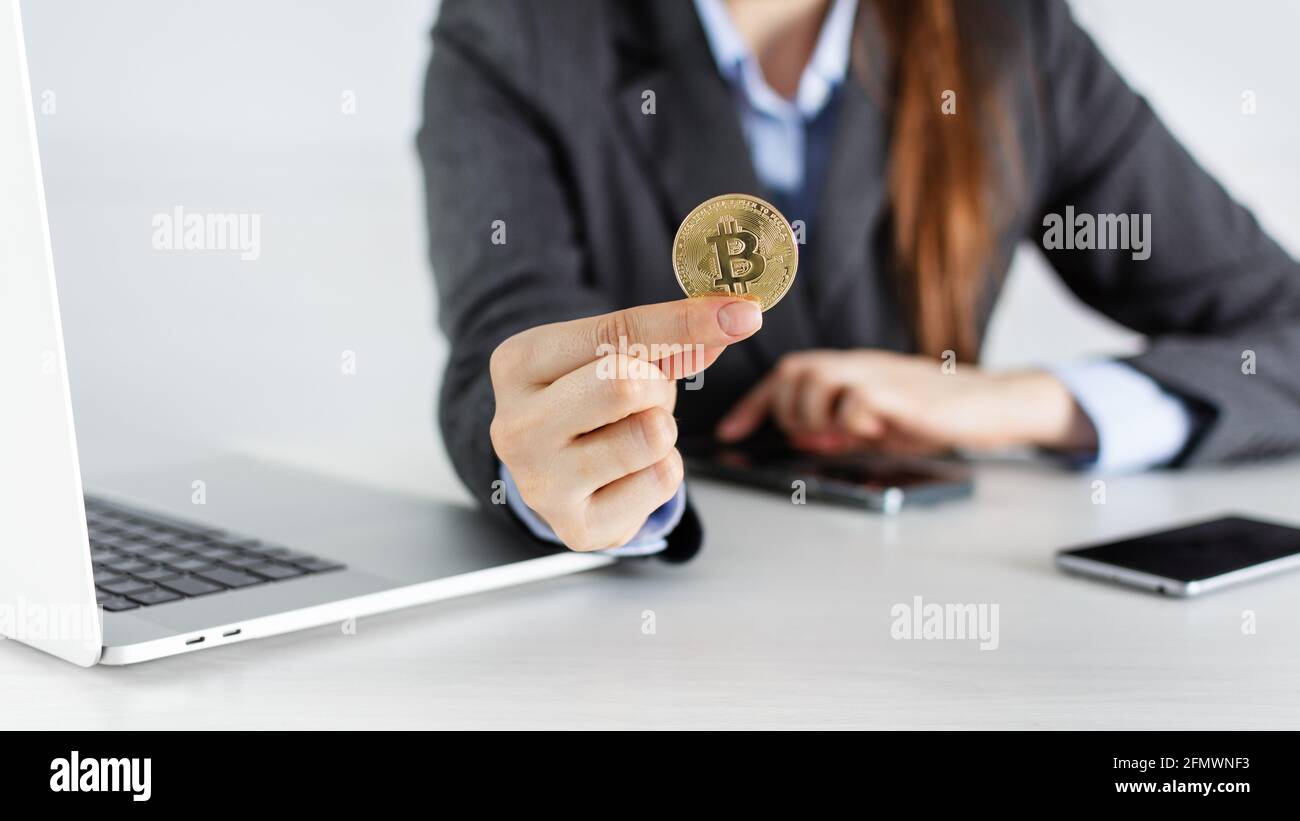 Businesswoman trader holding bitcoin cryptocurrency in the office with  laptop and smartphones. Cryptocurrency stock market concept Stock Photo -  Alamy