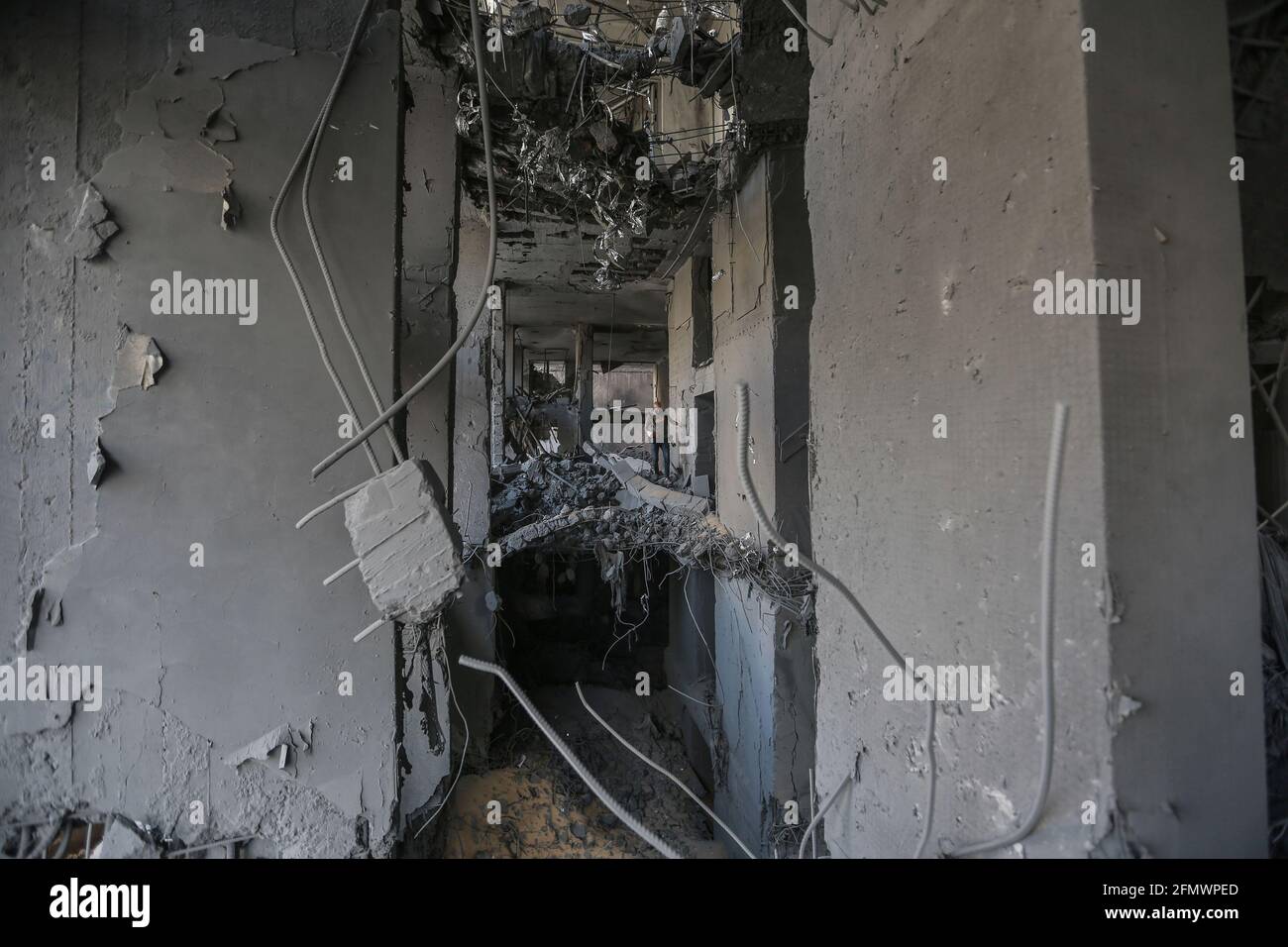 Gaza City, Palestinian Territories. 12th May, 2021. A photographer inspects the severely damaged Al-Jawhara Tower in Gaza City after it was hit by Israeli airstrikes amid the escalating flare-up of Israeli-Palestinian violence. The Health Ministry in the Hamas-run Gaza Strip said the number of Palestinians killed has risen to 35, including 12 children, while 233 people were reported injured. Credit: Mohammed Talatene/dpa/Alamy Live News Stock Photo