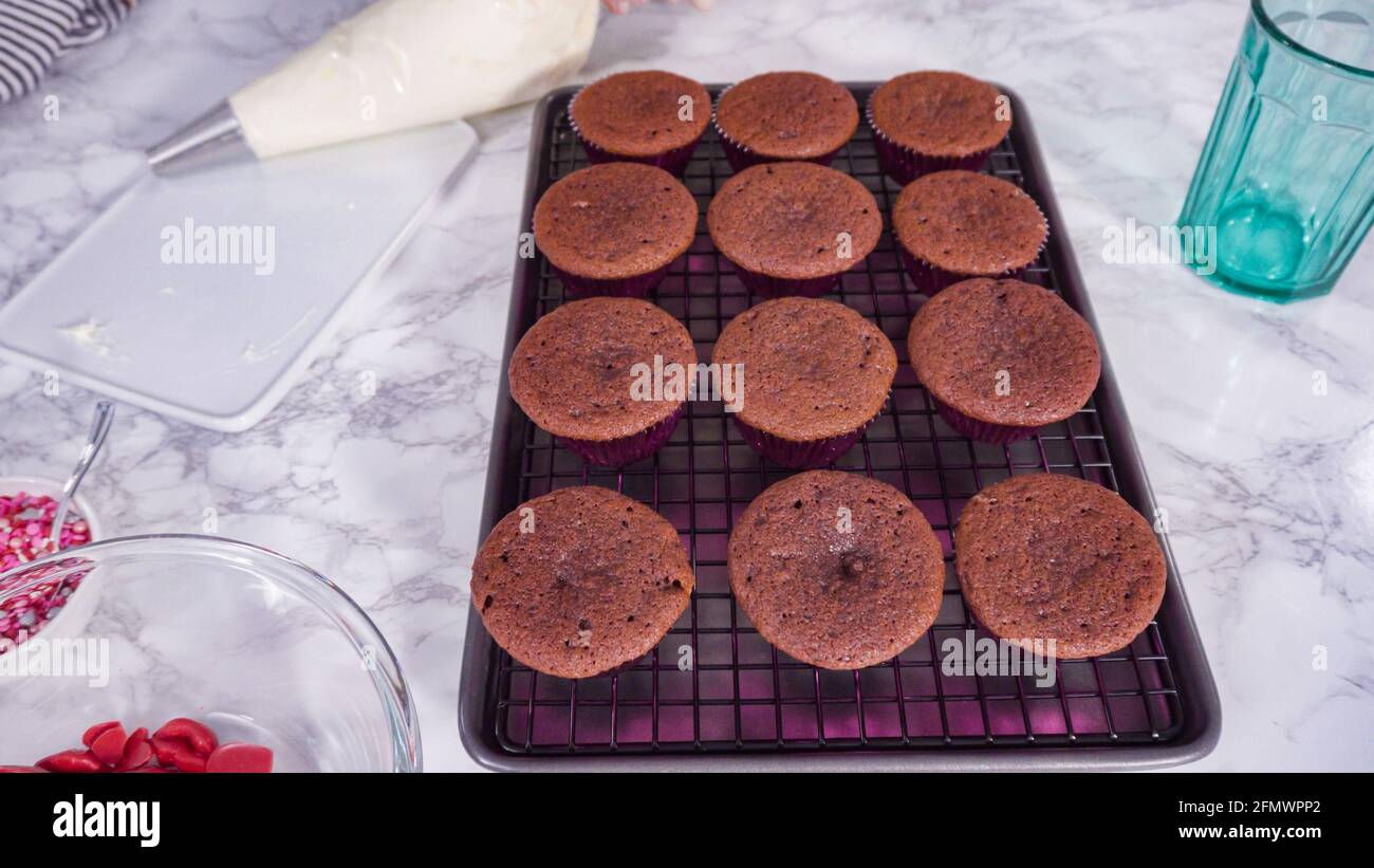 Step by step. Cooling red velvet cupcakes on a kitchen drying rack. Stock Photo