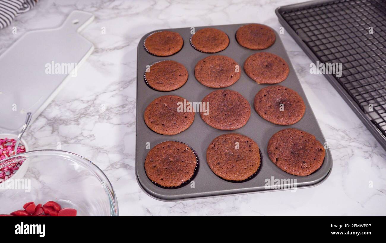 Step by step. Cooling red velvet cupcakes on a kitchen drying rack. Stock Photo