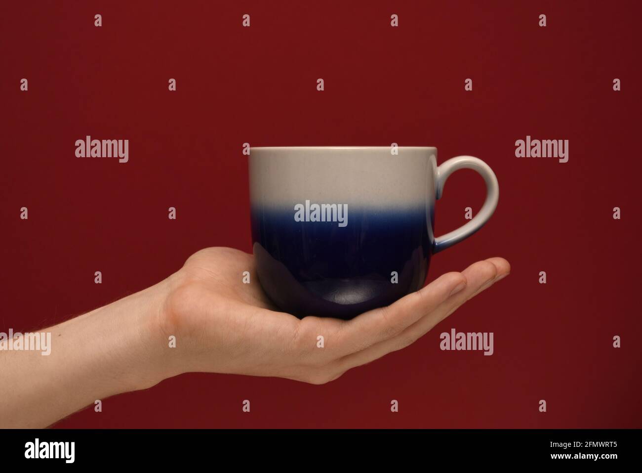 Hand holding a cup on a red background Stock Photo