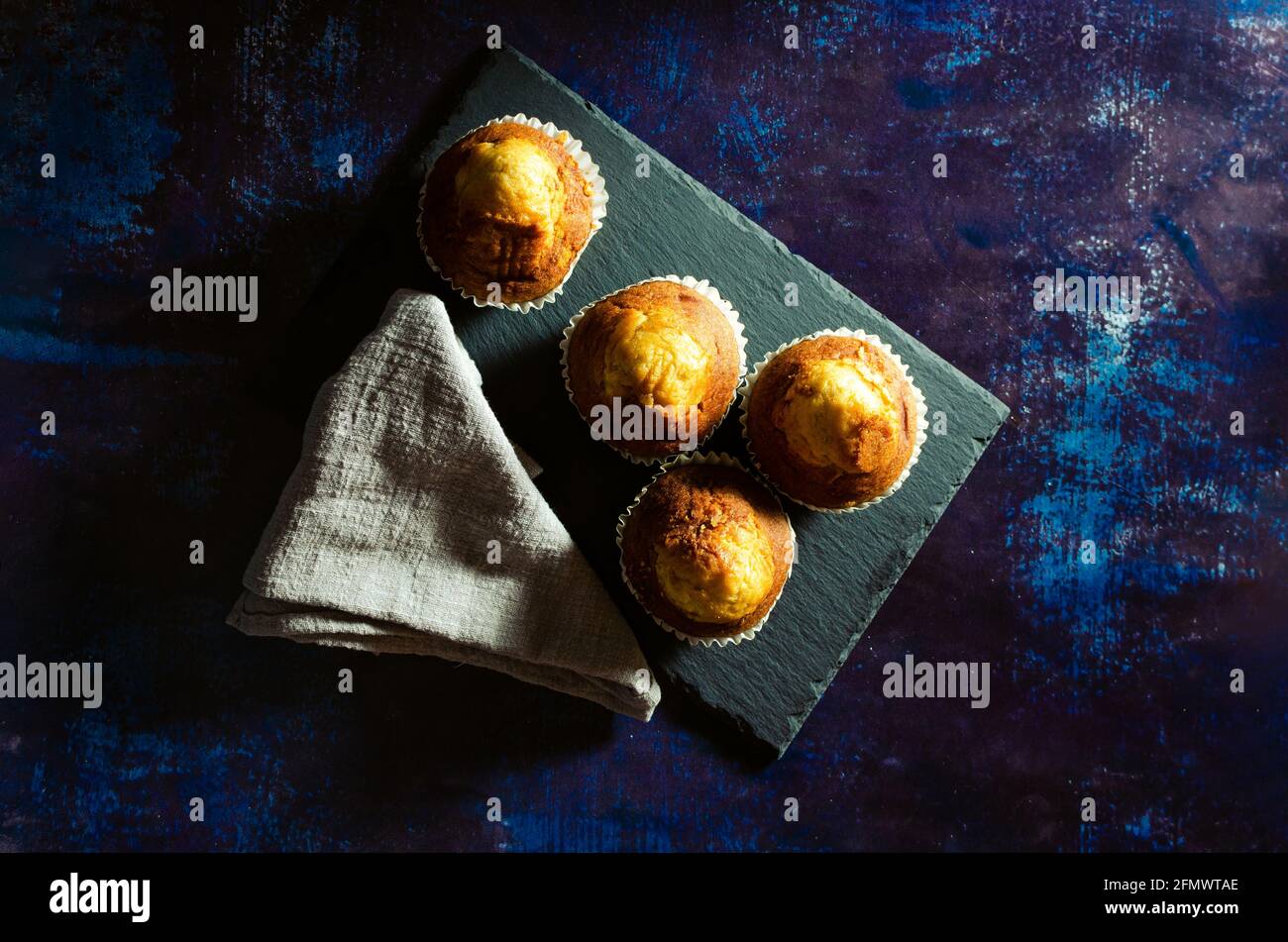 Muffins on a slate plate on a rusty blue background with a linen cloth. Dark Food Stock Photo
