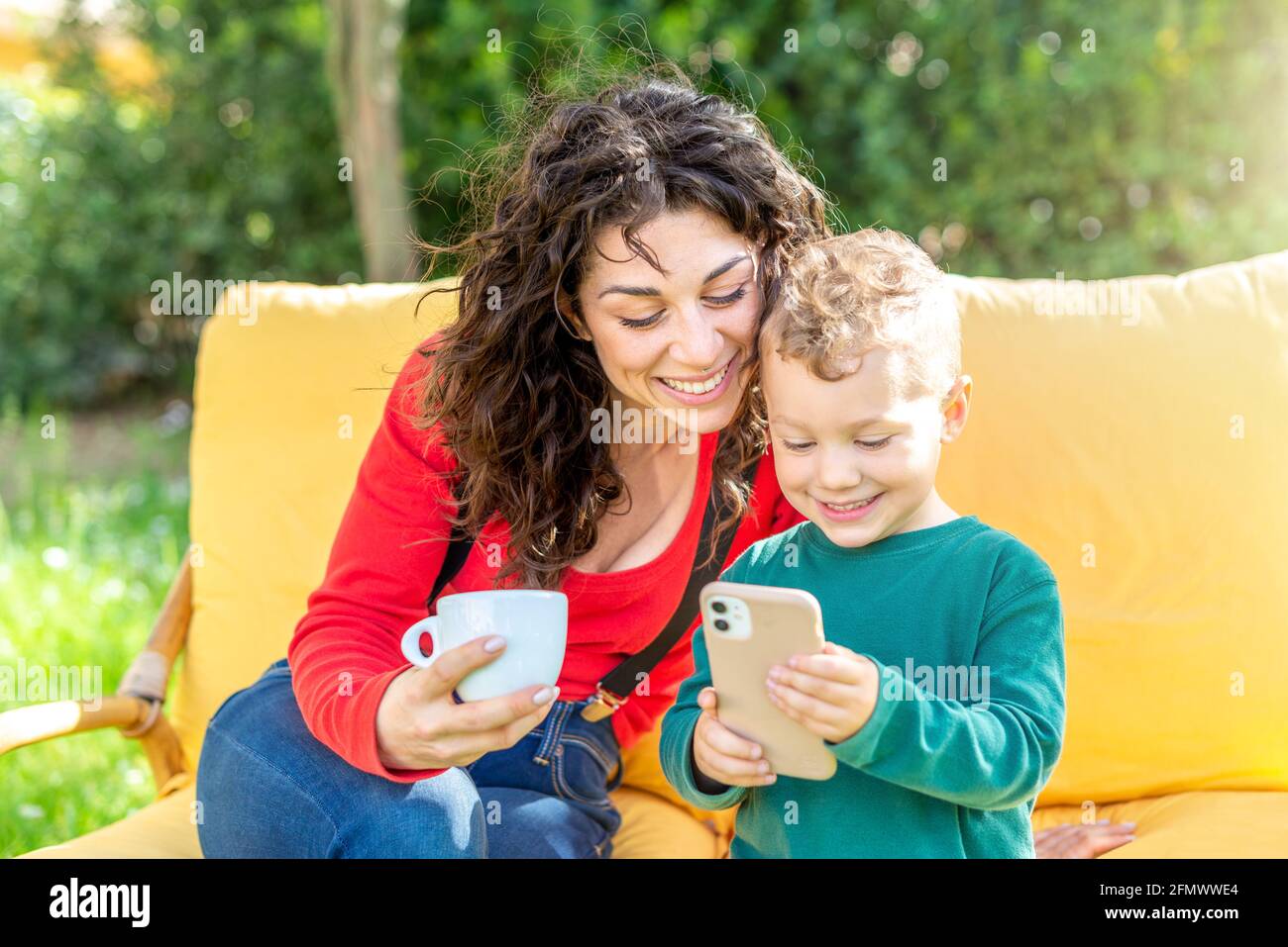 happy mom and son chilling outdoor sitting on couch in public park garden  watching funny videos on  woman and child interacting  Stock Photo - Alamy