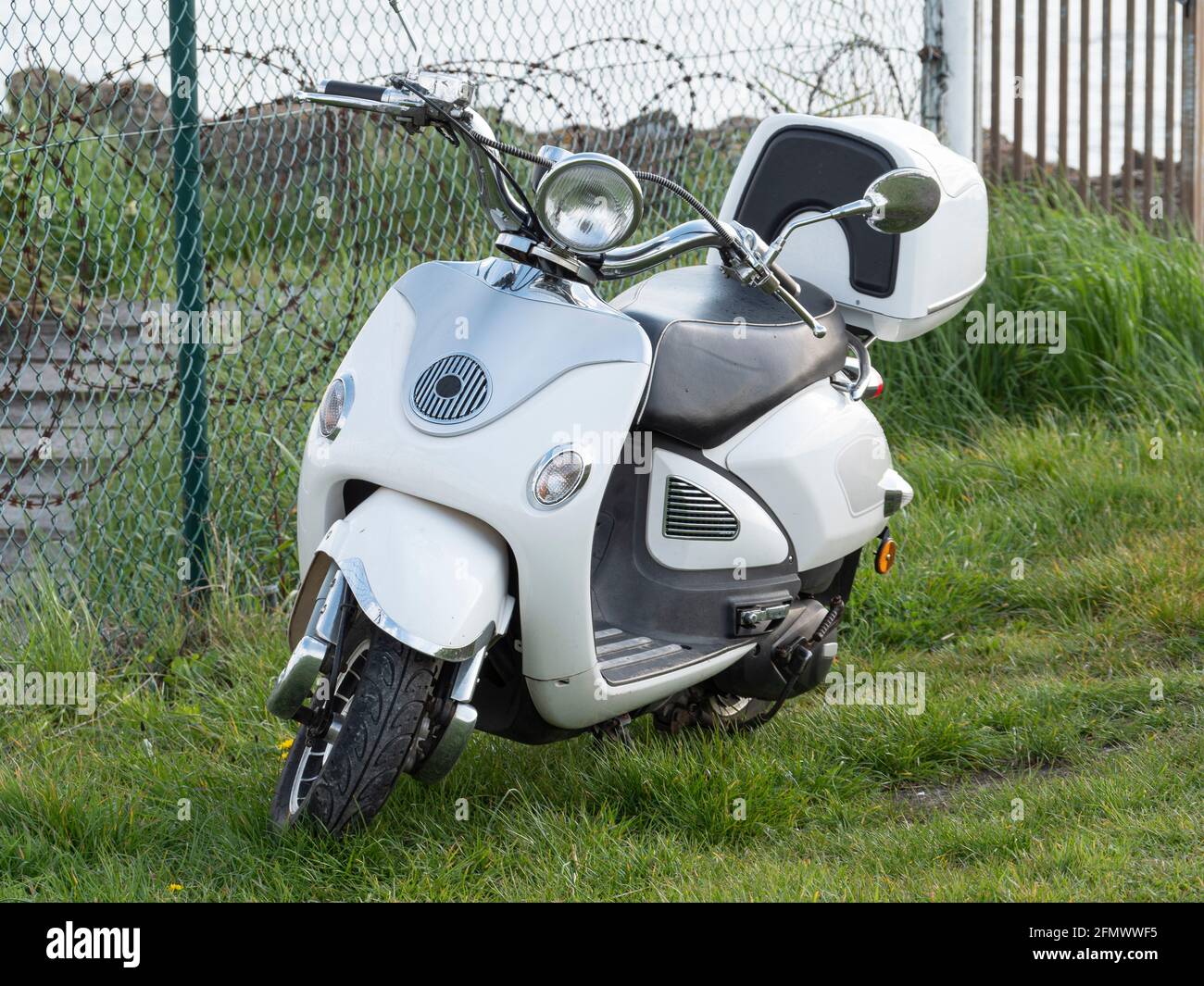 White vintage scooter is parked in the grass Stock Photo