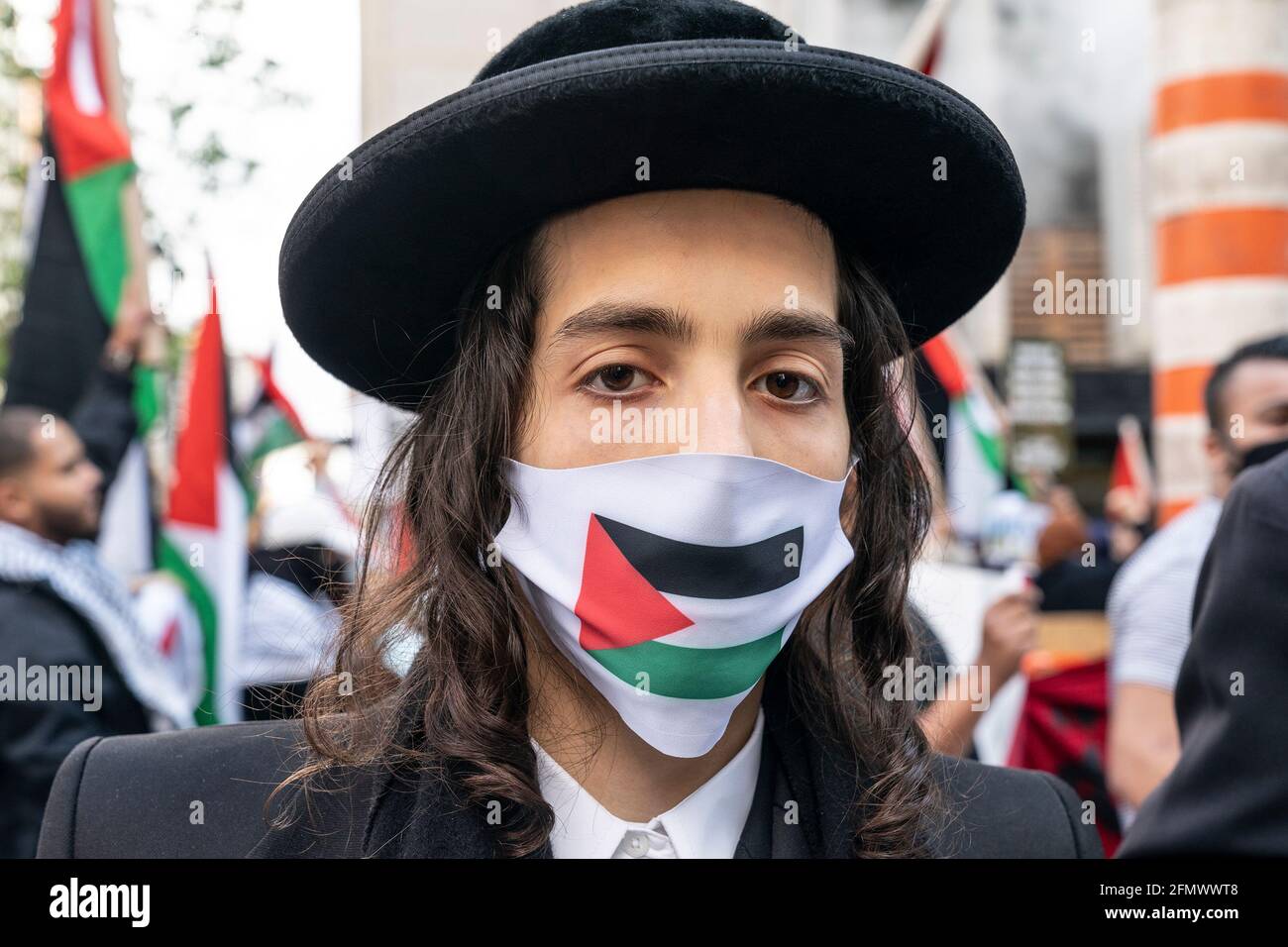 Hundreds of people participated in a rally and march in support of Palestine on 42nd street in Manhattan in New York on May 11, 2021. Protesters rally in support of Palestinians who clashed with Israeli police in anticipation of a court ruling to evict them from some places in East Jerusalem. Protesters were joined by some Orthodox Jews from Anti-Zionists sect Neturei Karta who oppose the state of Israel. Many protesters were wearing Palestinian scarf - keffiyeh. There was also a counter protest by about two dozen Jewish supporters of Israel, but they were vastly outnumbered by supporters of P Stock Photo