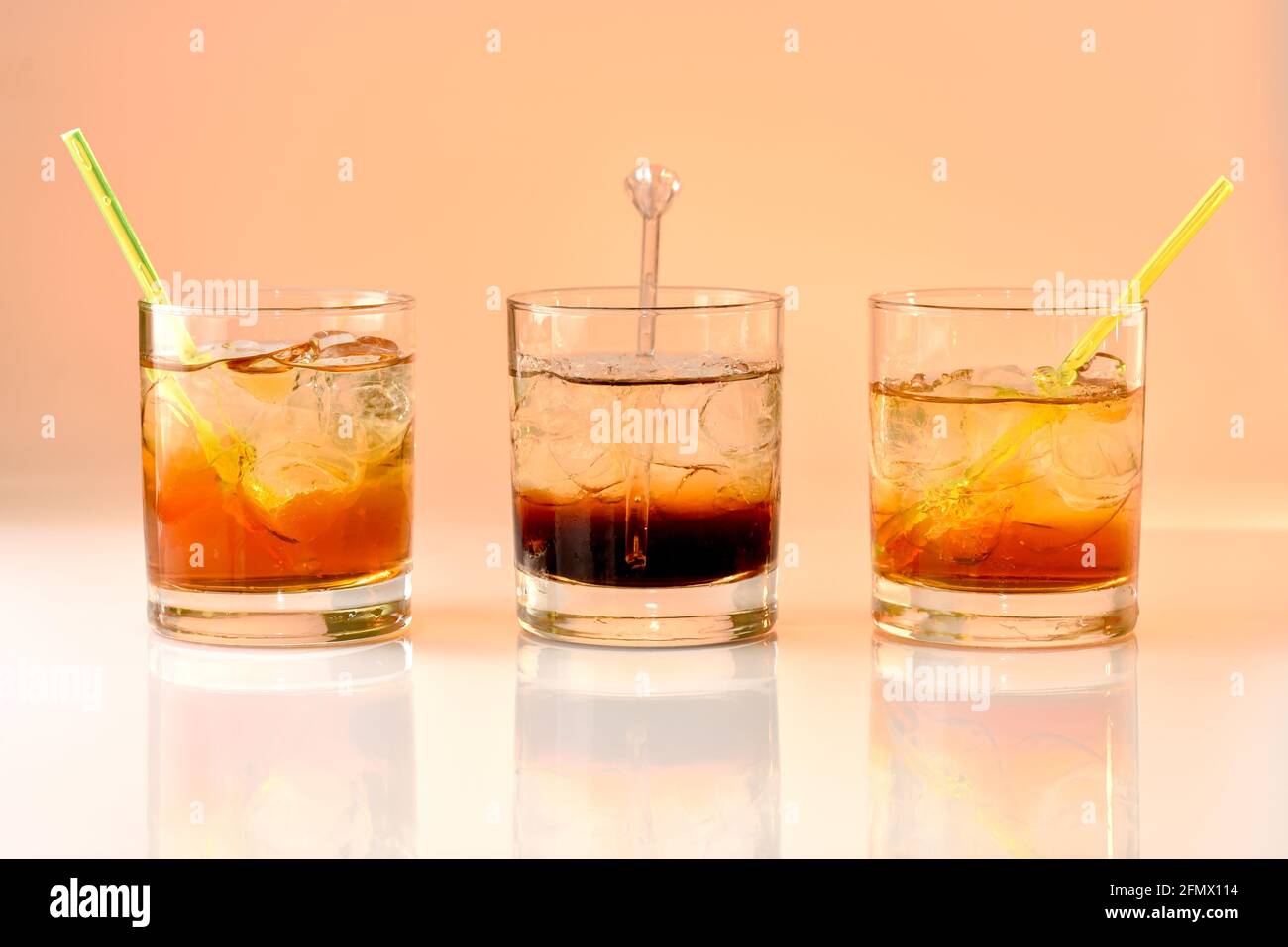 three cocktails on orange background, god mother, Black Russian and god father in glass with ice Stock Photo