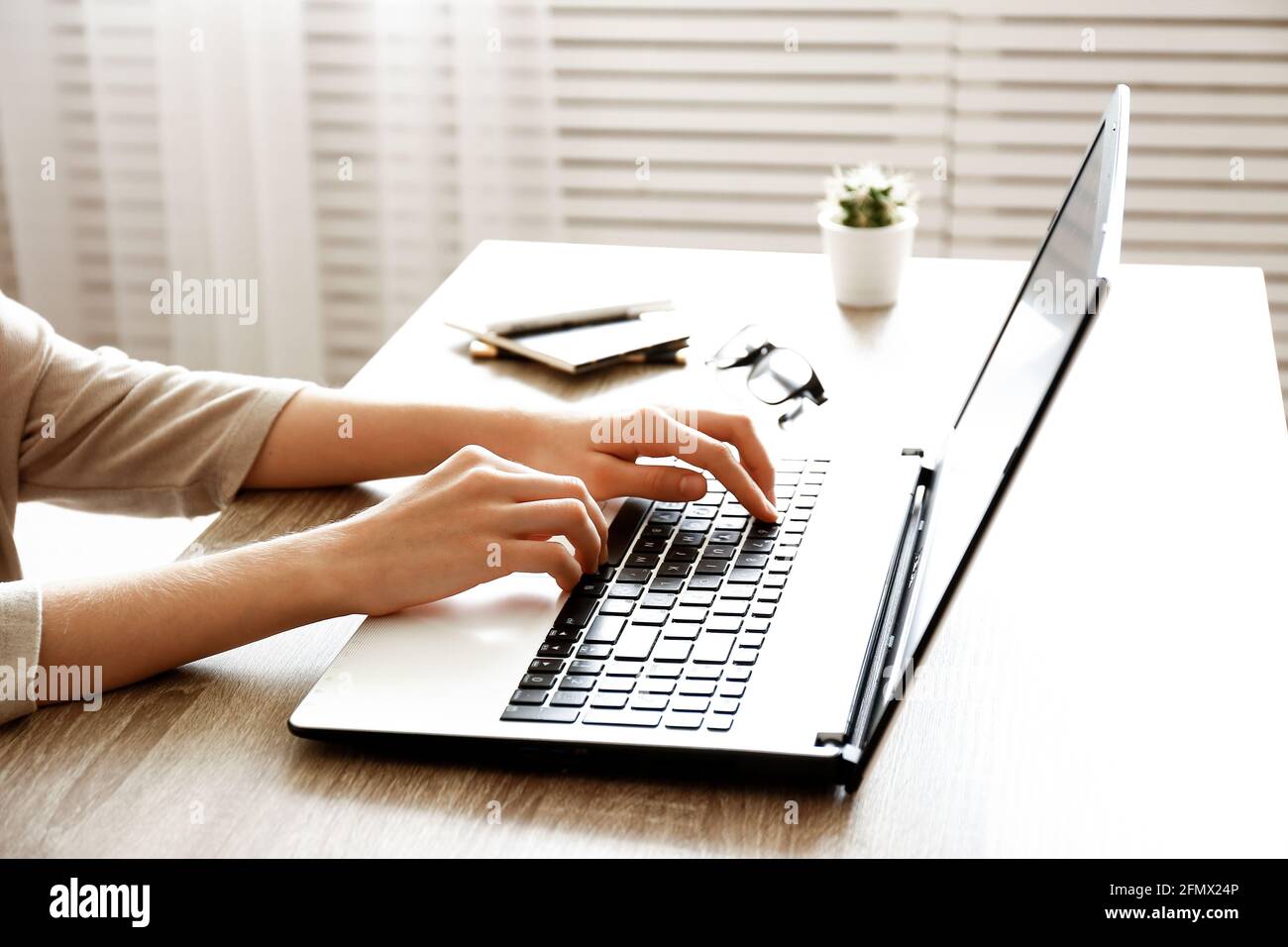 Top view of Young woman surfing internet, coding, online shopping, close up of hands on her laptop keyboard on wood textured office desk. Overhead sho Stock Photo