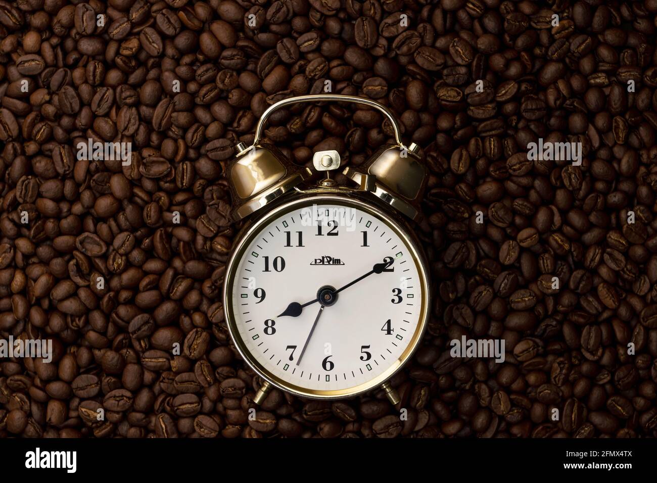 Old alarm clock with coffee beans background Stock Photo