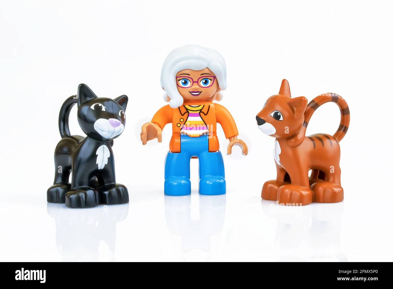 KHARKIV, UKRAINE - March 29th, 2020: Toy old lady with two toy cats, plastic toys, pre-school education theme, isolated on white Stock Photo