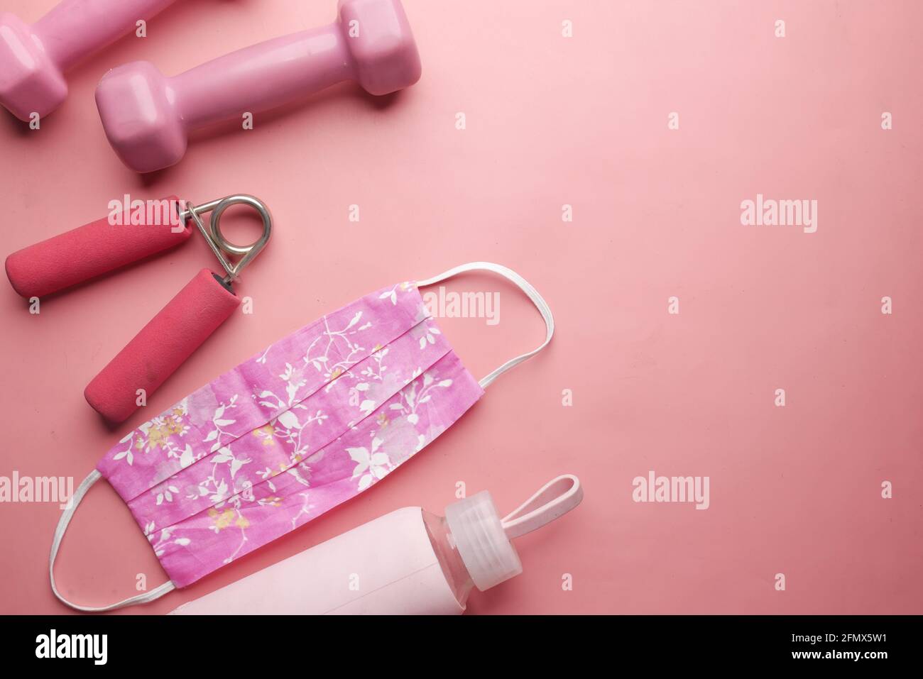 pink color dumbbell, , water bottle and homemade mask on pink  Stock Photo